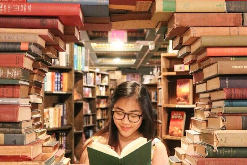 woman in green shirt sitting on books